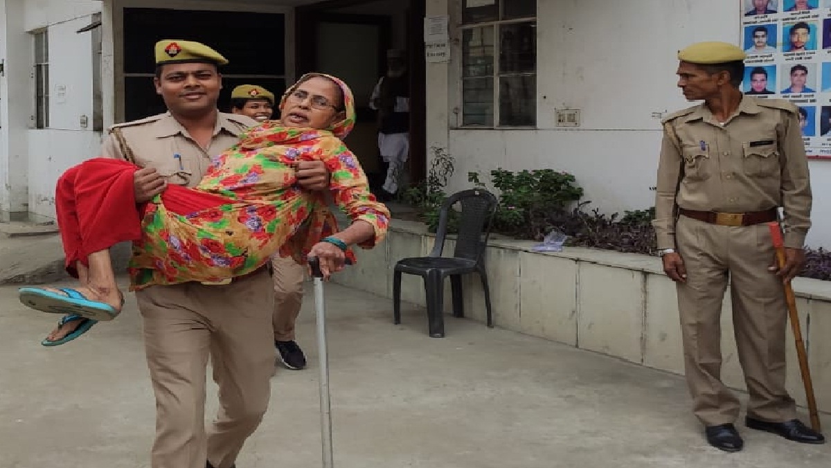 The soldier carrying the old woman voter in his lap.